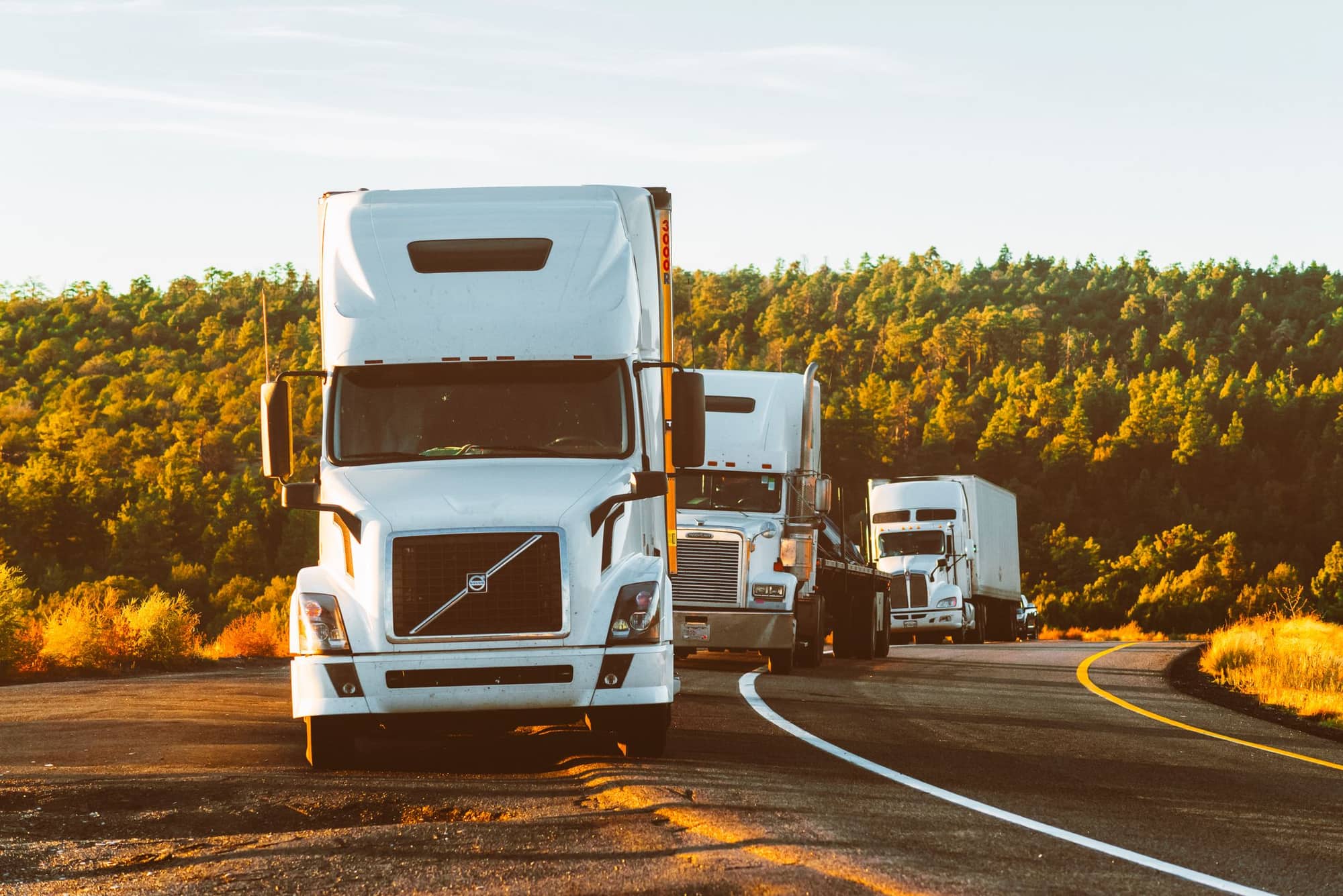 POAK Global Transports freight trucks on the interstate at golden hour